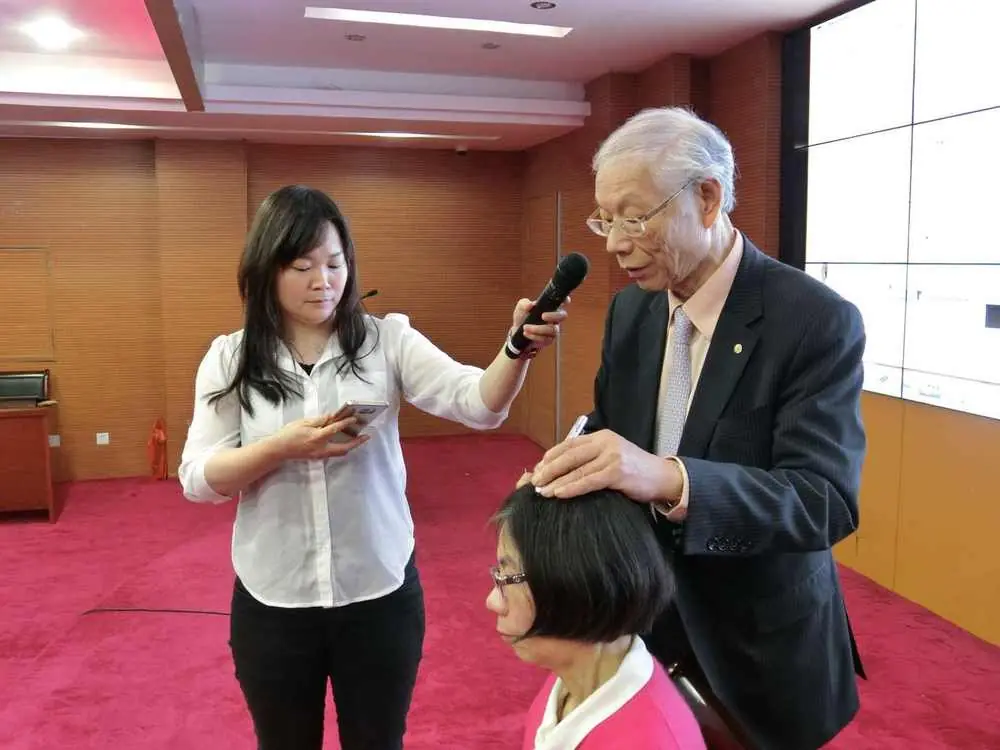 Professor Ming Qing Zhu demonstrating Zhu's Scalp Acupuncture (ZSA) technique during a lecture, with Dr. Shy and Dr. Moyee Siu, 2017.
